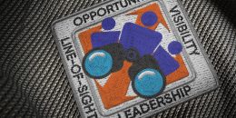 "Leading Change" illustration by Chris Fraser. A knitted square with a binocular graphic sits in the center of a black-and-white fabric. The words Opportunity, Visibility, Leadership, and Line-of-Sight sit on each site of the border.